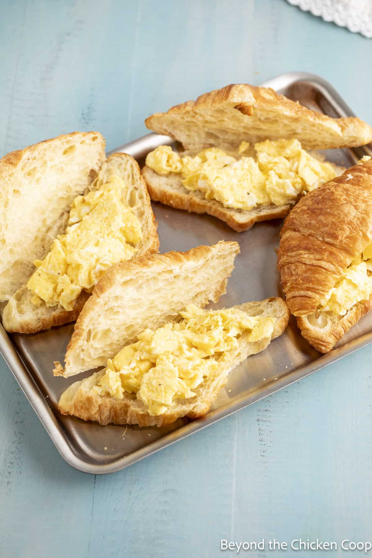 Croissants cut in half topped with scrambled eggs.