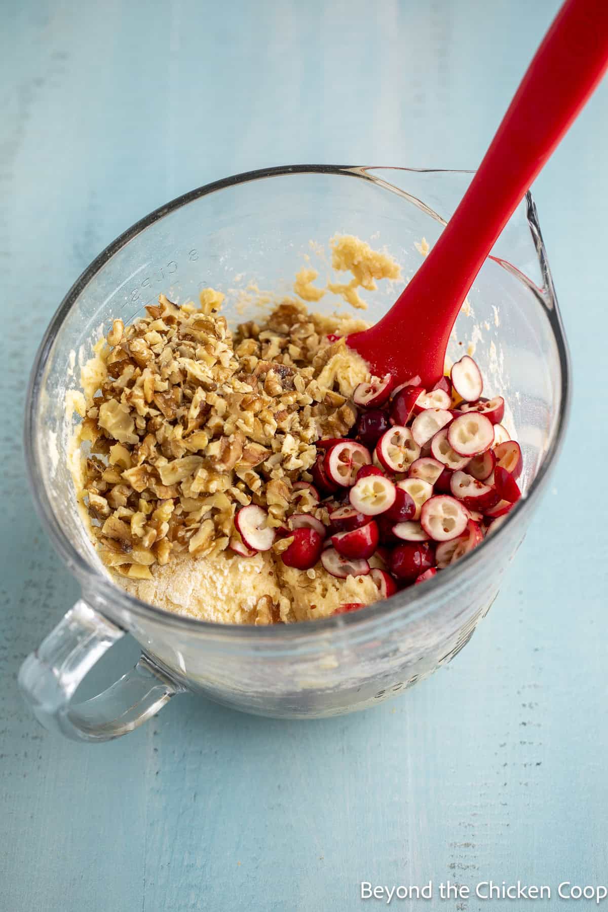 Muffin batter with chopped cranberries and walnuts.