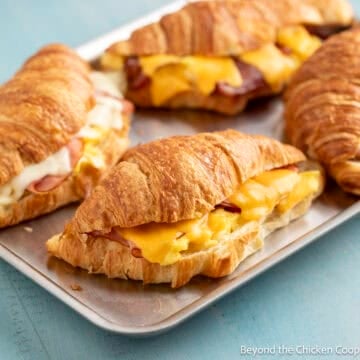 Croissant breakfast sandwiches with ham, bacon, and cheese.