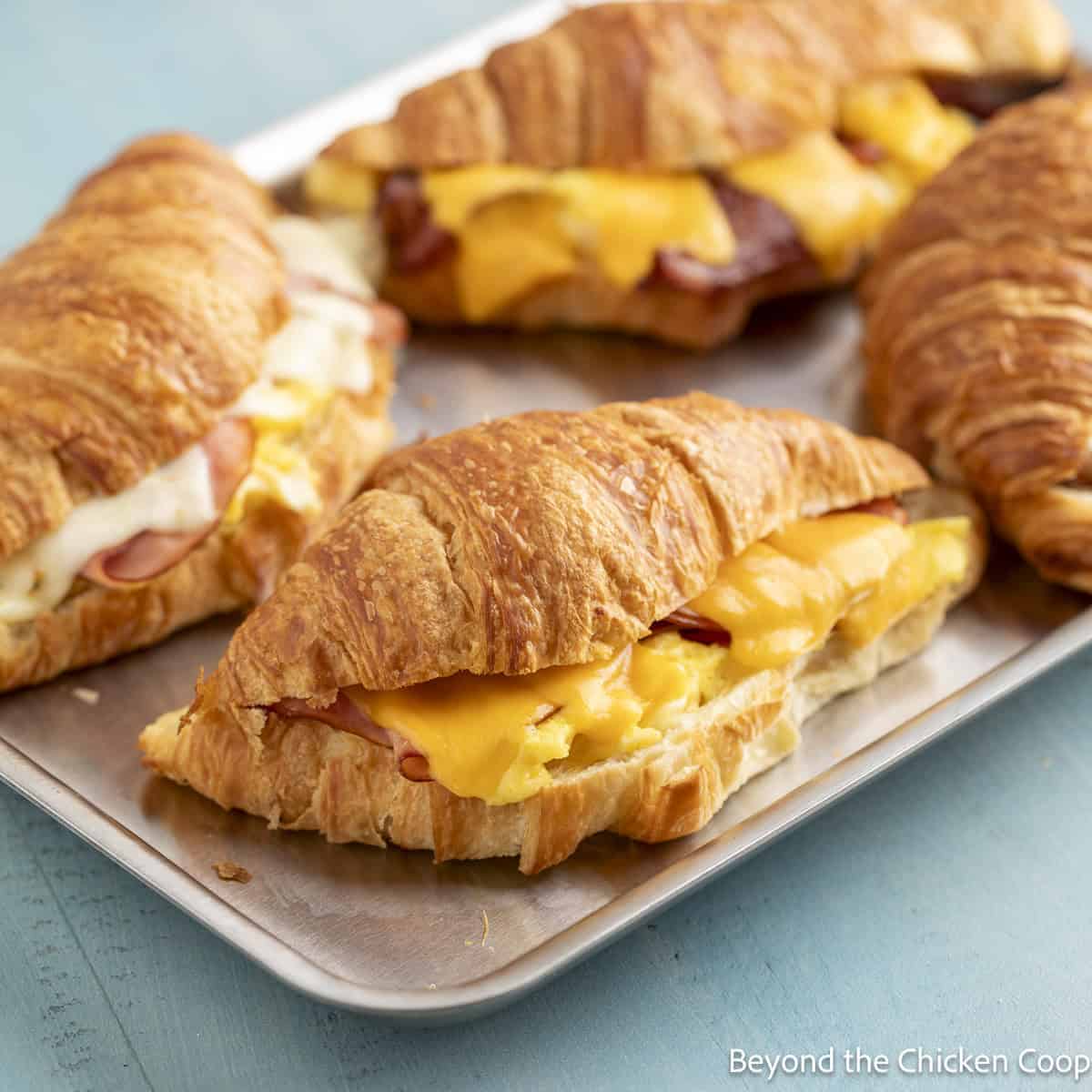Croissant breakfast sandwiches with ham, bacon, and cheese.