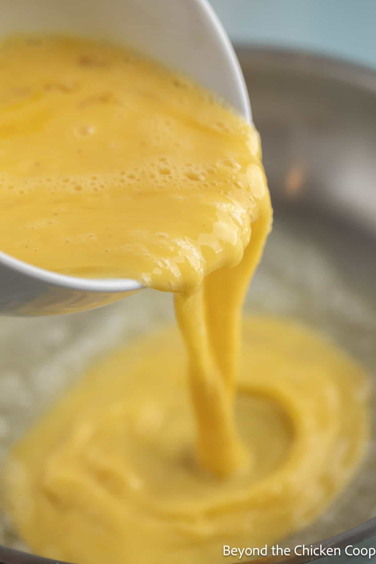 Pouring scrambled eggs into a pan.