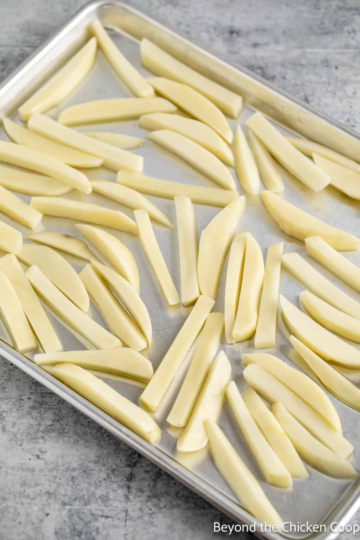 Uncooked fries on a baking sheet.