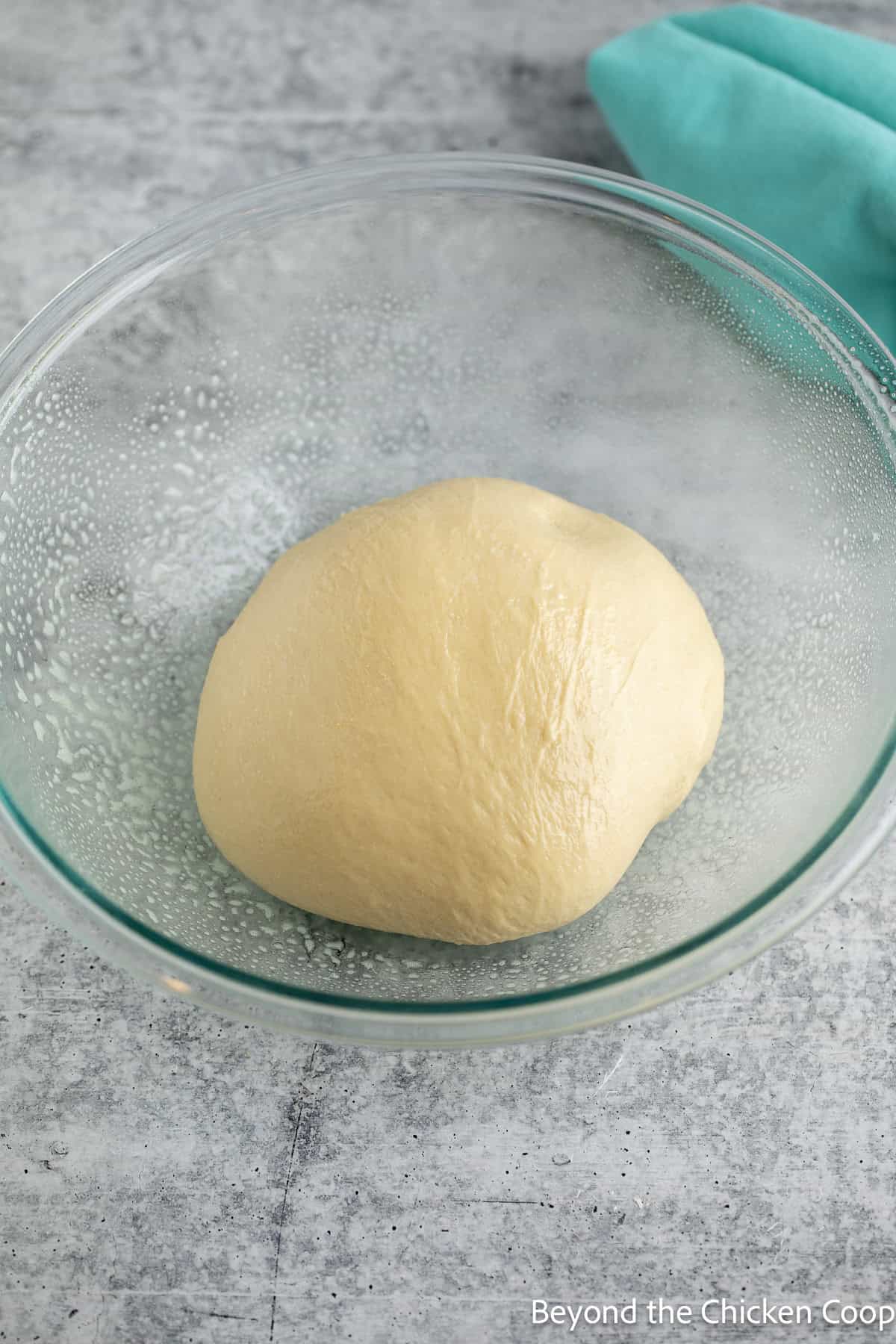 A ball of dough in a glass bowl.