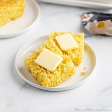 Sliced homemade cornbread with pats of butter.