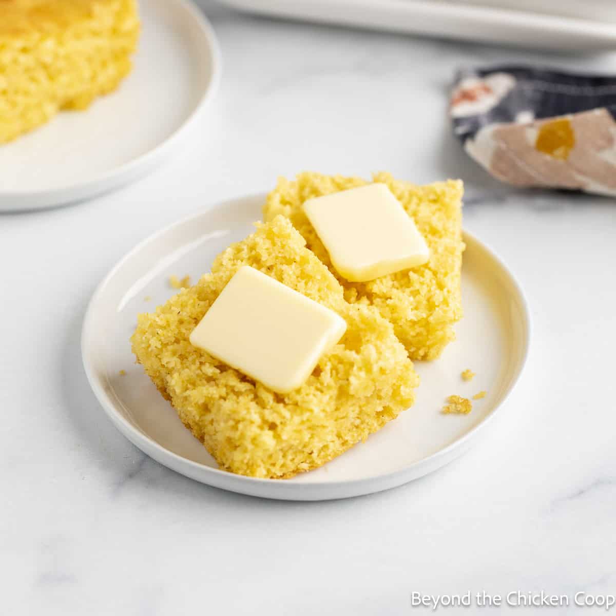 Sliced homemade cornbread with pats of butter.
