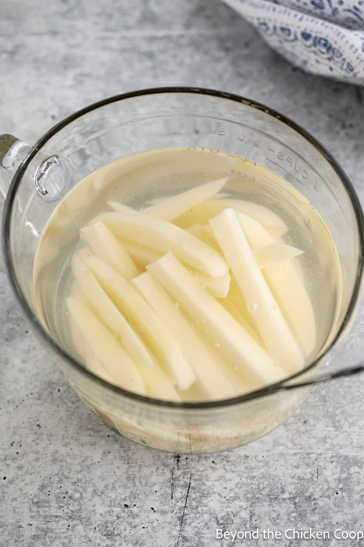 Soaking potatoes in a bowl of water.