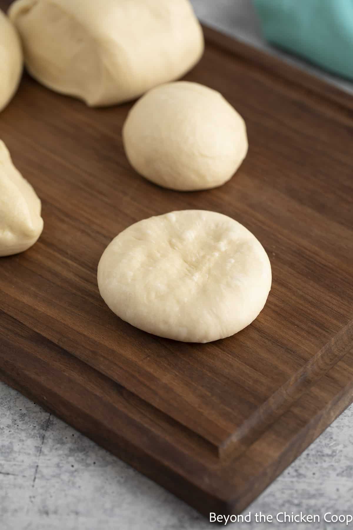 Shaping hamburger buns on a wooden board.