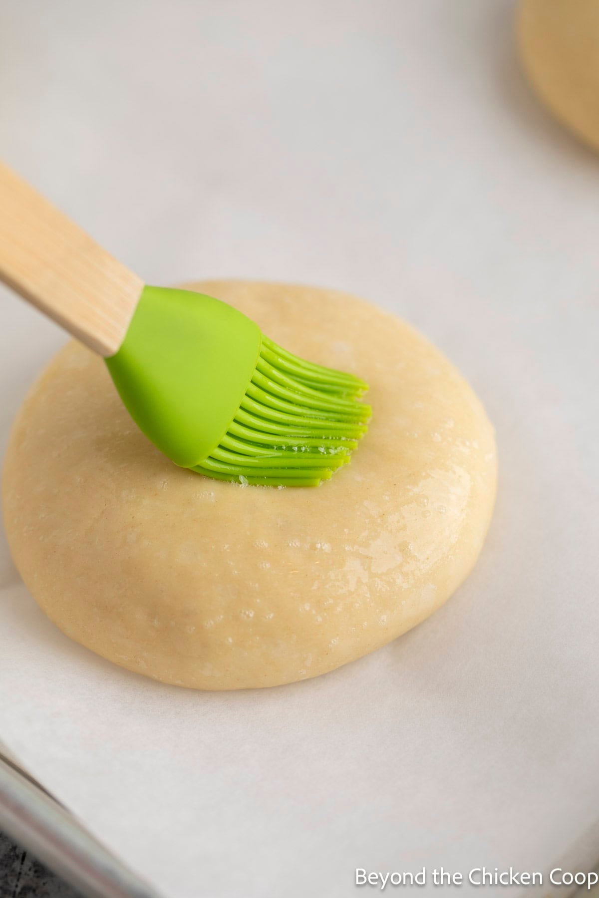Brushing an egg wash onto hamburger buns.