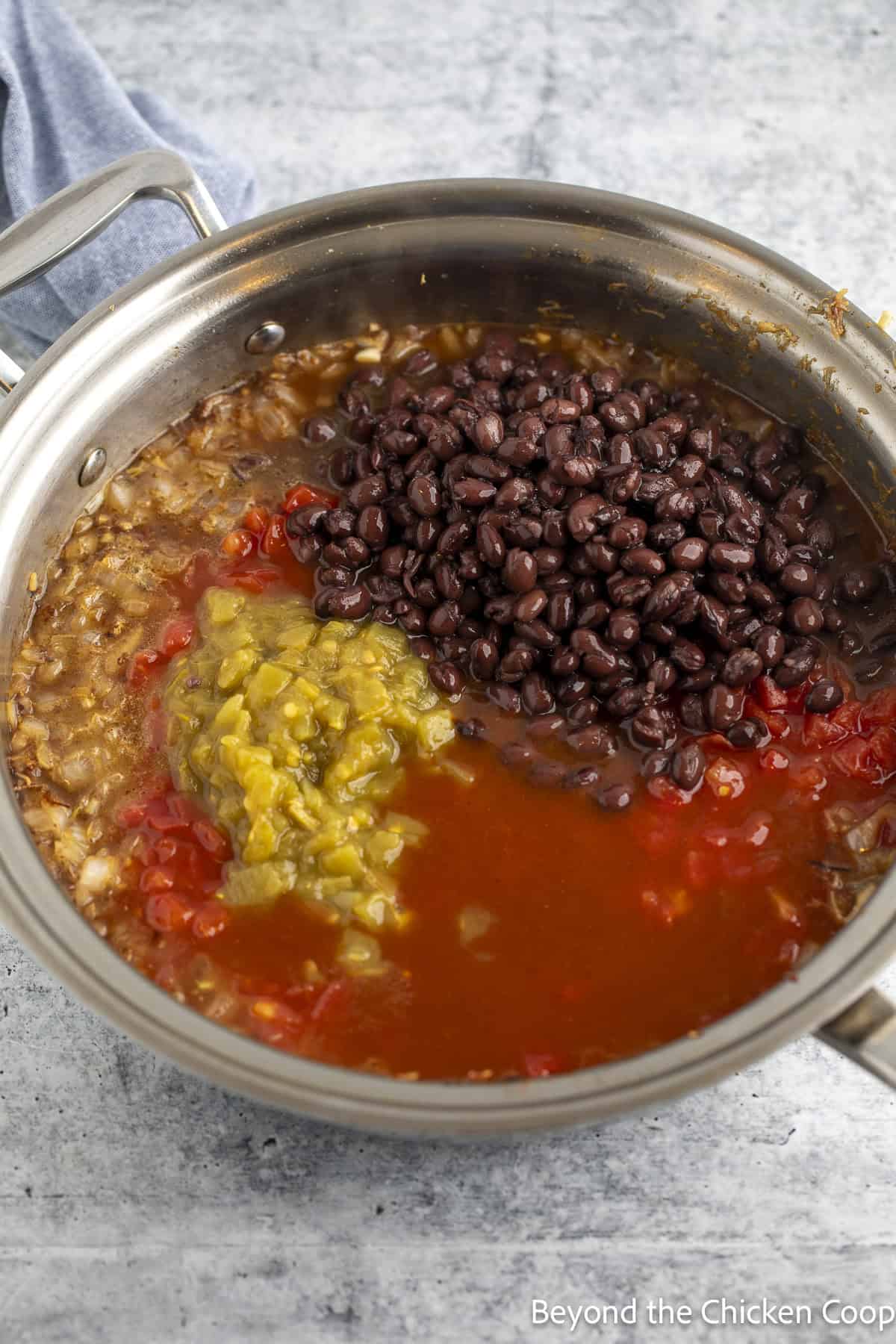 A skillet with canned tomatoes, green chiles, and black beans.