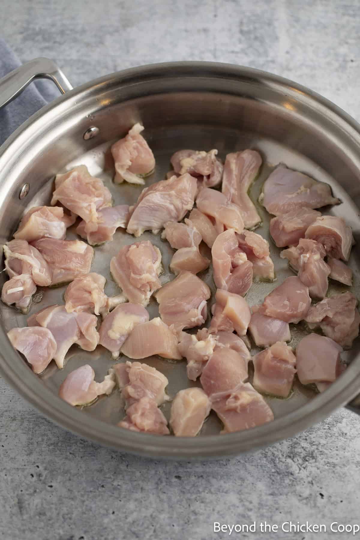 Cubed chicken cooking in a large skillet.