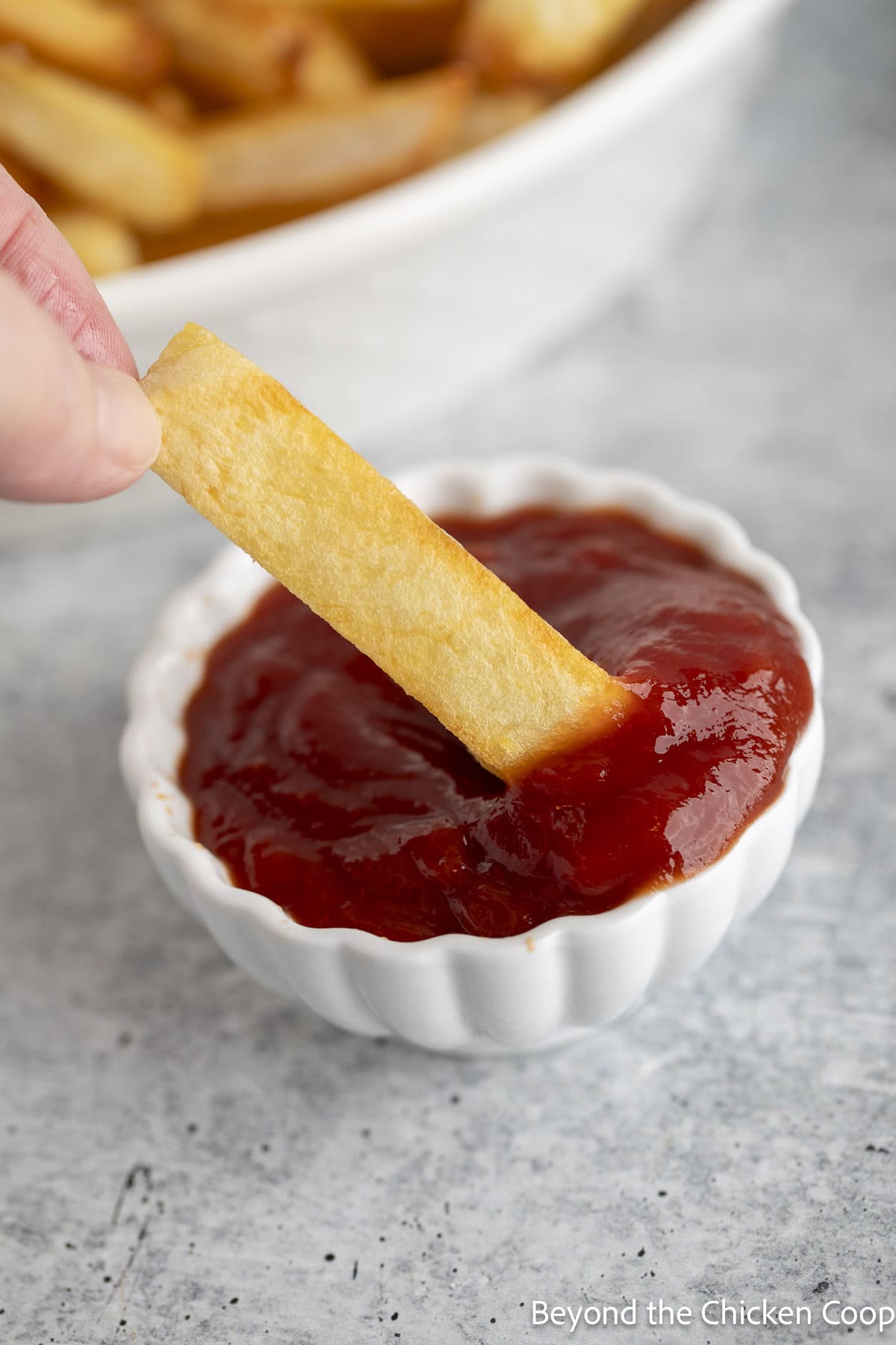 Dipping a french fry into ketchup.