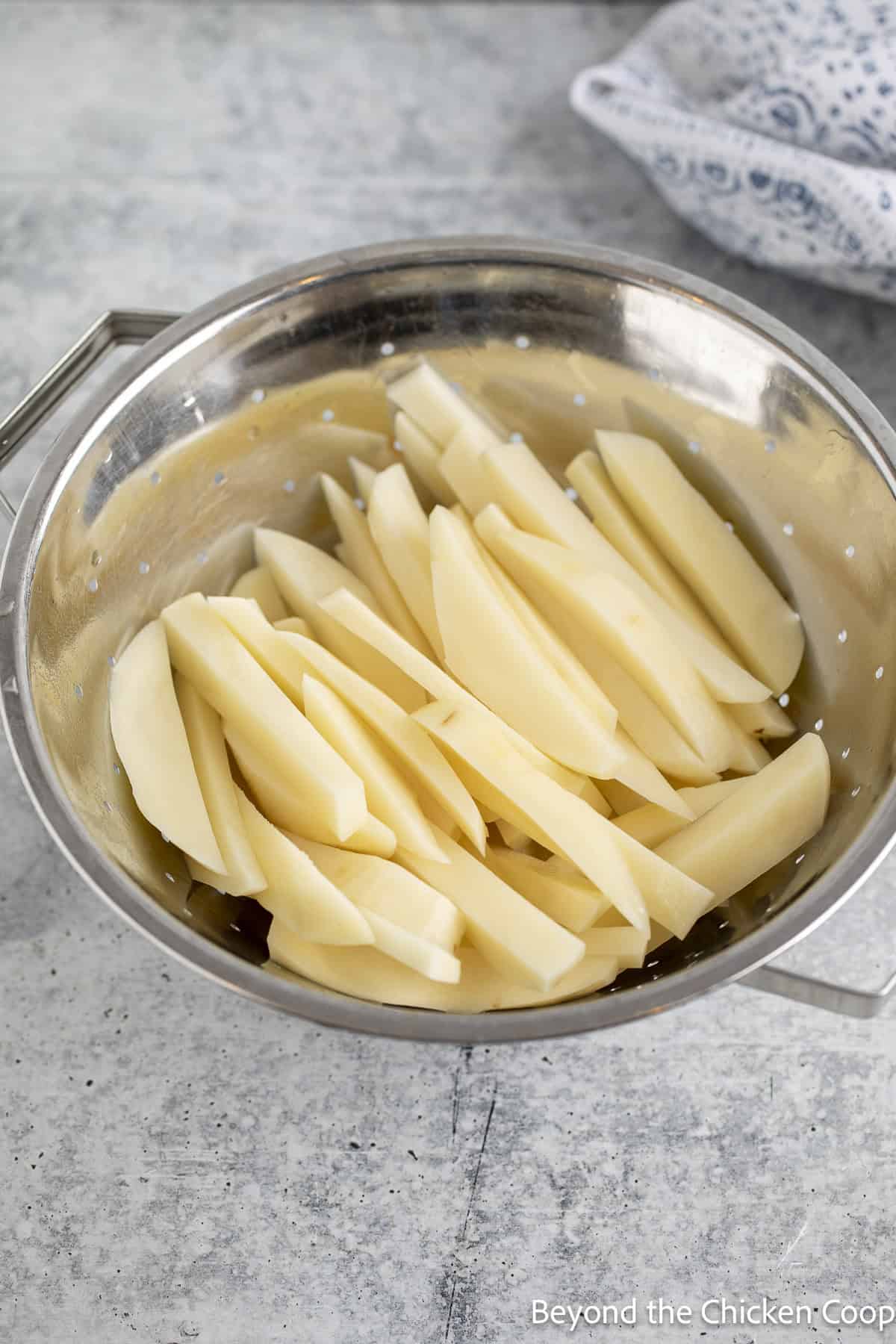 Drained potato slices in a colander.