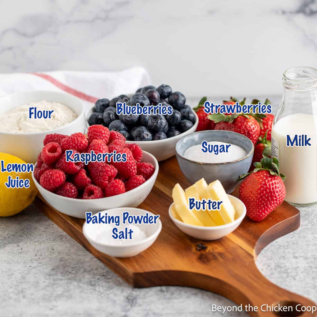 Bowls of raspberries, blueberries by a bowl of sugar, butter and flour.