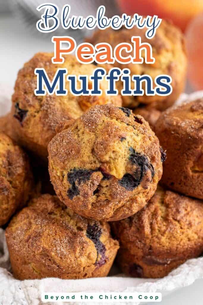 A basket filled with muffins with blueberries and peaches.