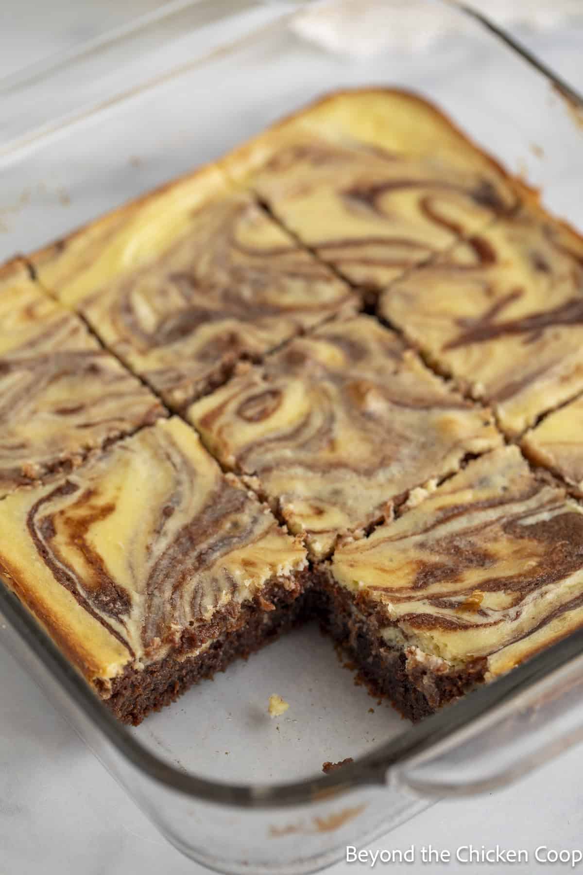 Baked cheesecake brownies in a glass baking dish.