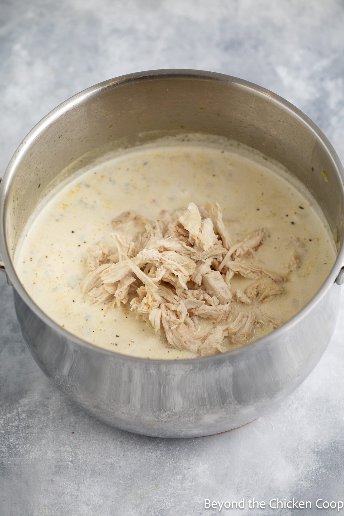 Adding shredded chicken to soup.