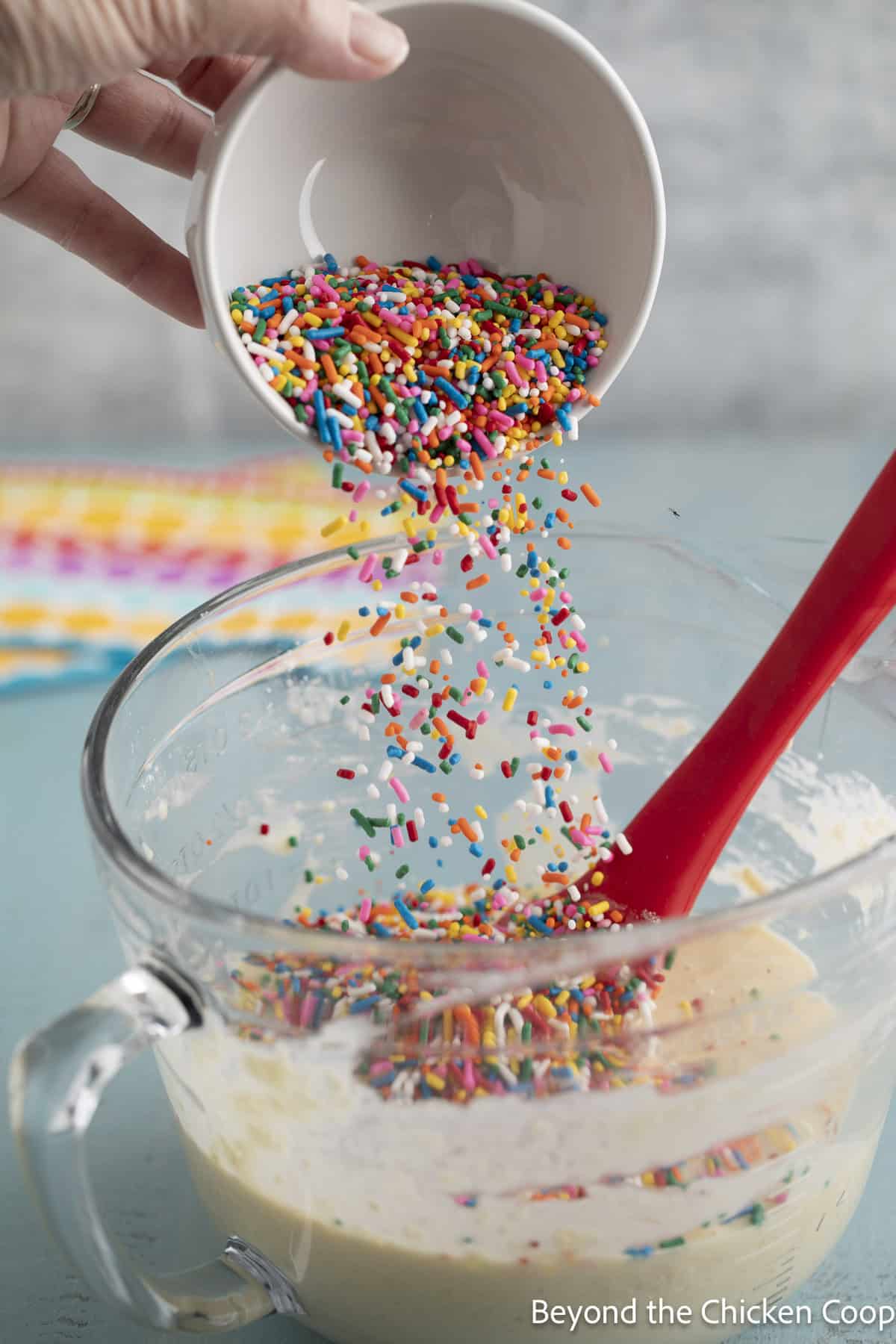 Sprinkles being poured into pancake batter.
