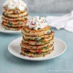 A stack of confetti pancakes topped with a dollop of whipped cream.