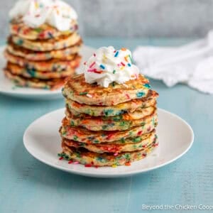 A stack of confetti pancakes topped with a dollop of whipped cream.