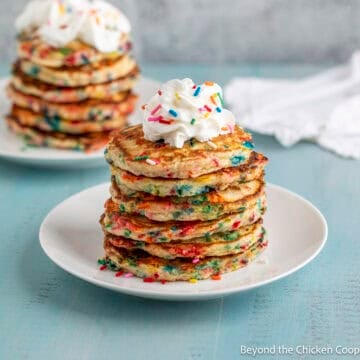 A stack of confetti pancakes topped with a dollop of whipped cream.