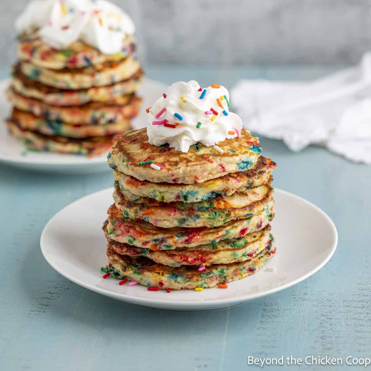 A stack of confetti pancakes topped with a dollop of whipped cream. 