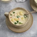 A mug filled with creamy chicken gnocchi soup.