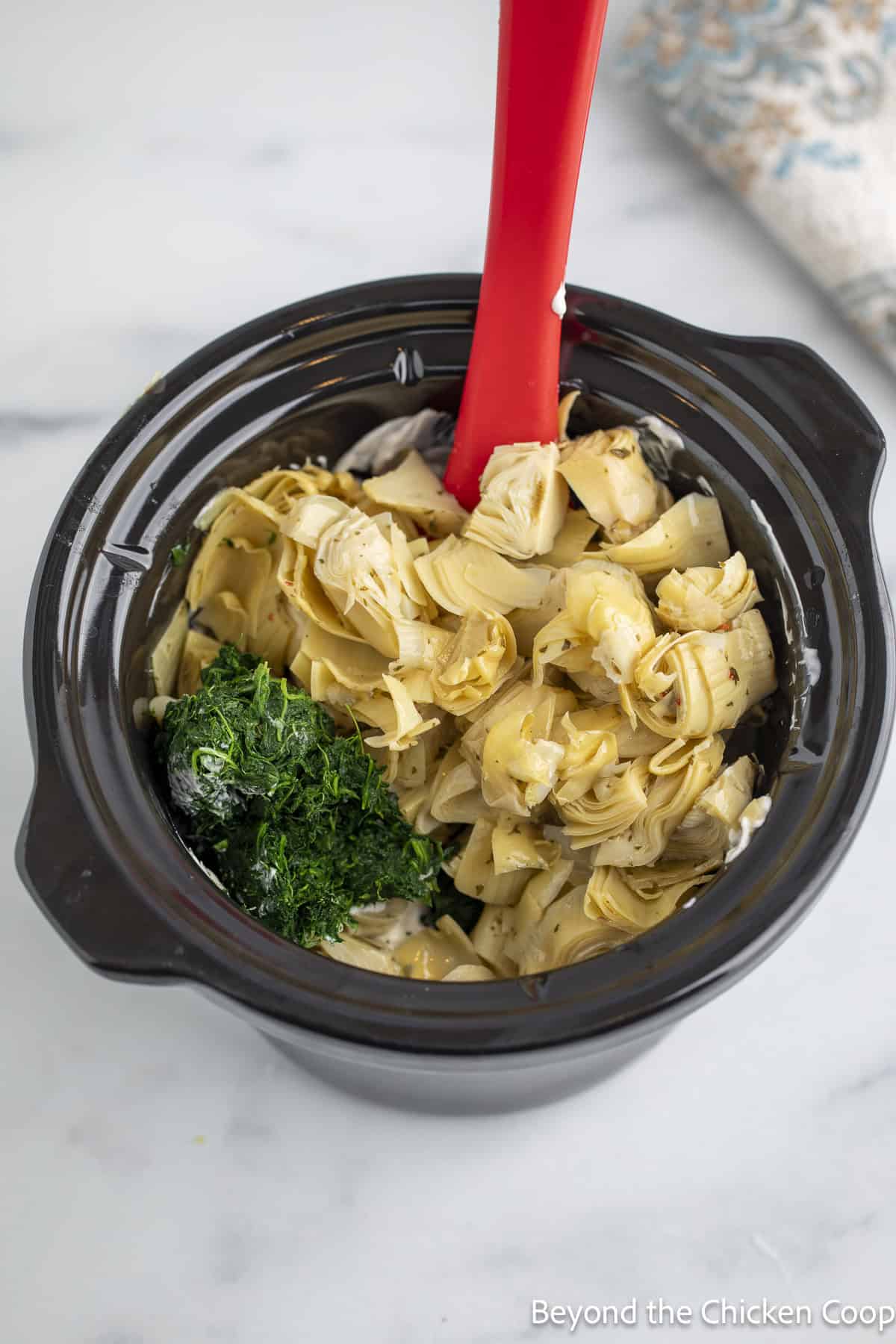 Artichoke hearts and spinach in a crock pot.
