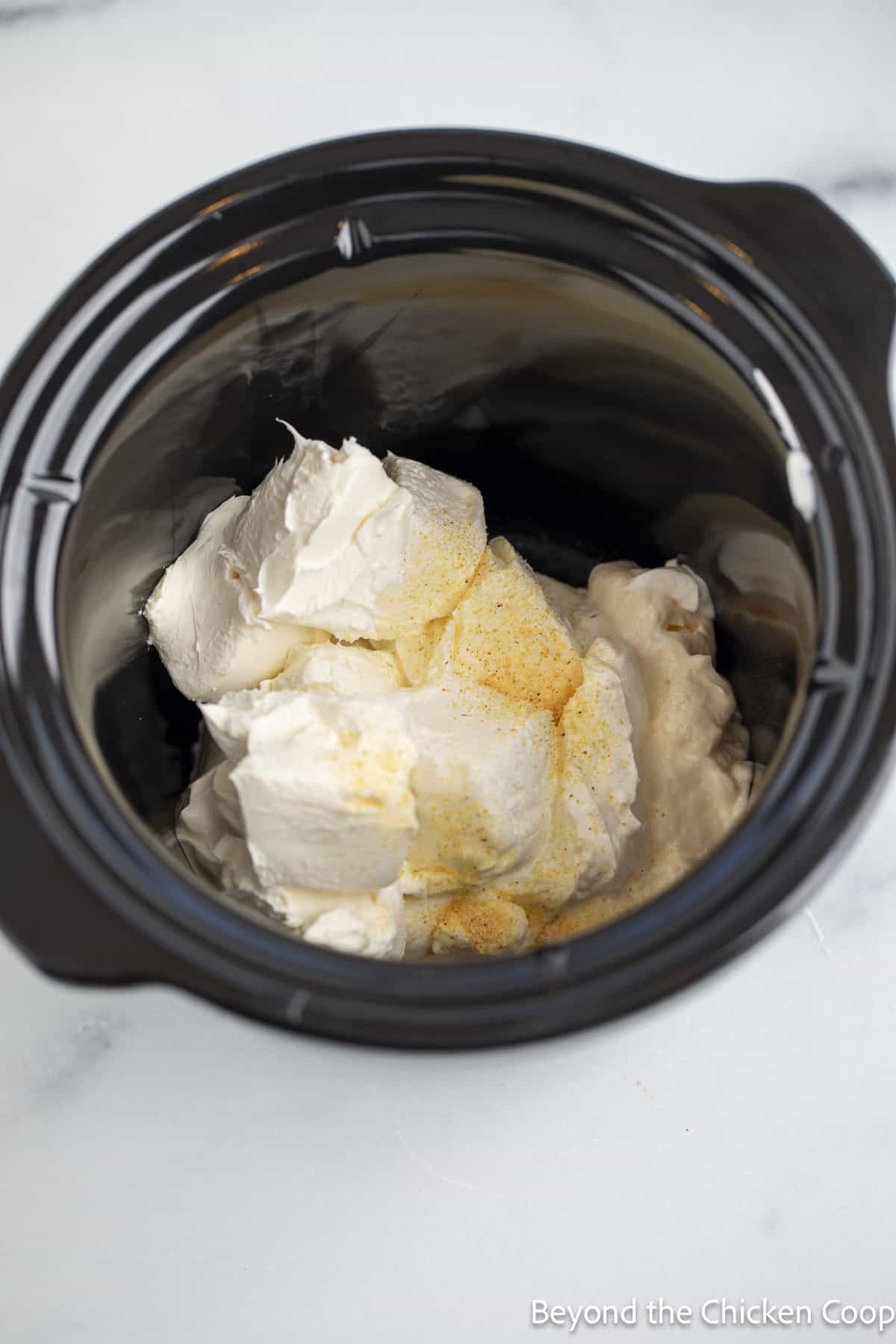 Cream cheese and seasoning in a crock pot.