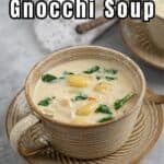 A bowl filled with a creamy soup with spinach and gnocchi.