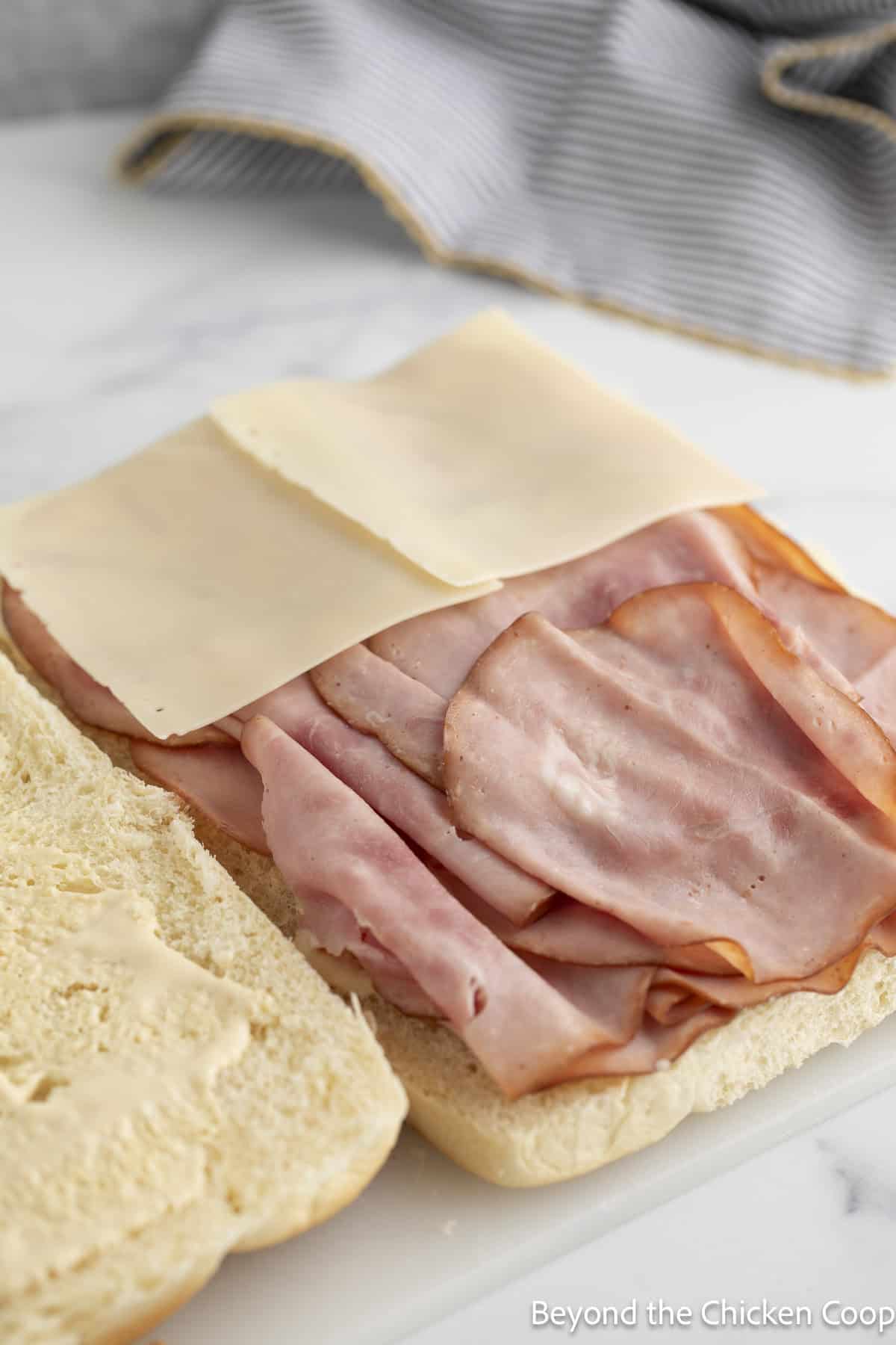 Layering ham and cheese on slider buns.