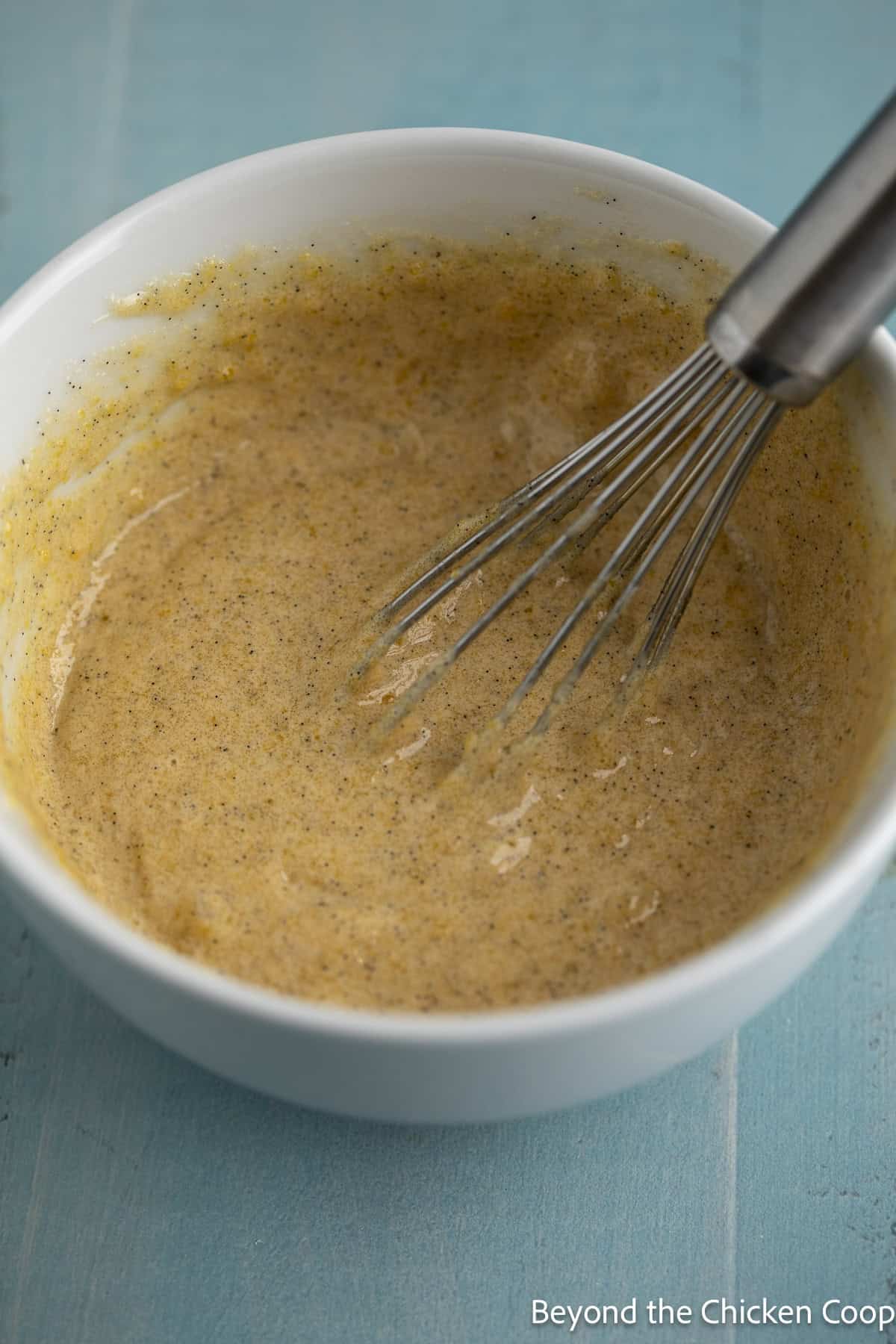 Egg yolks, sugar, and vanilla bean paste mixed in a bowl.