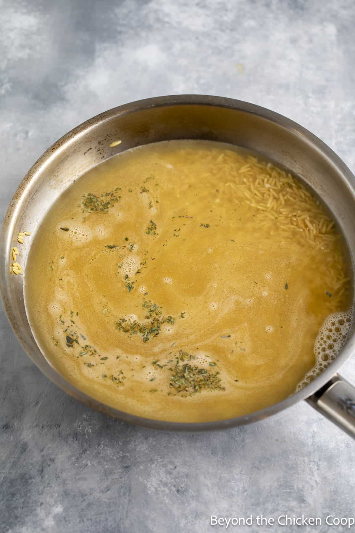 Chicken stock in a skillet.
