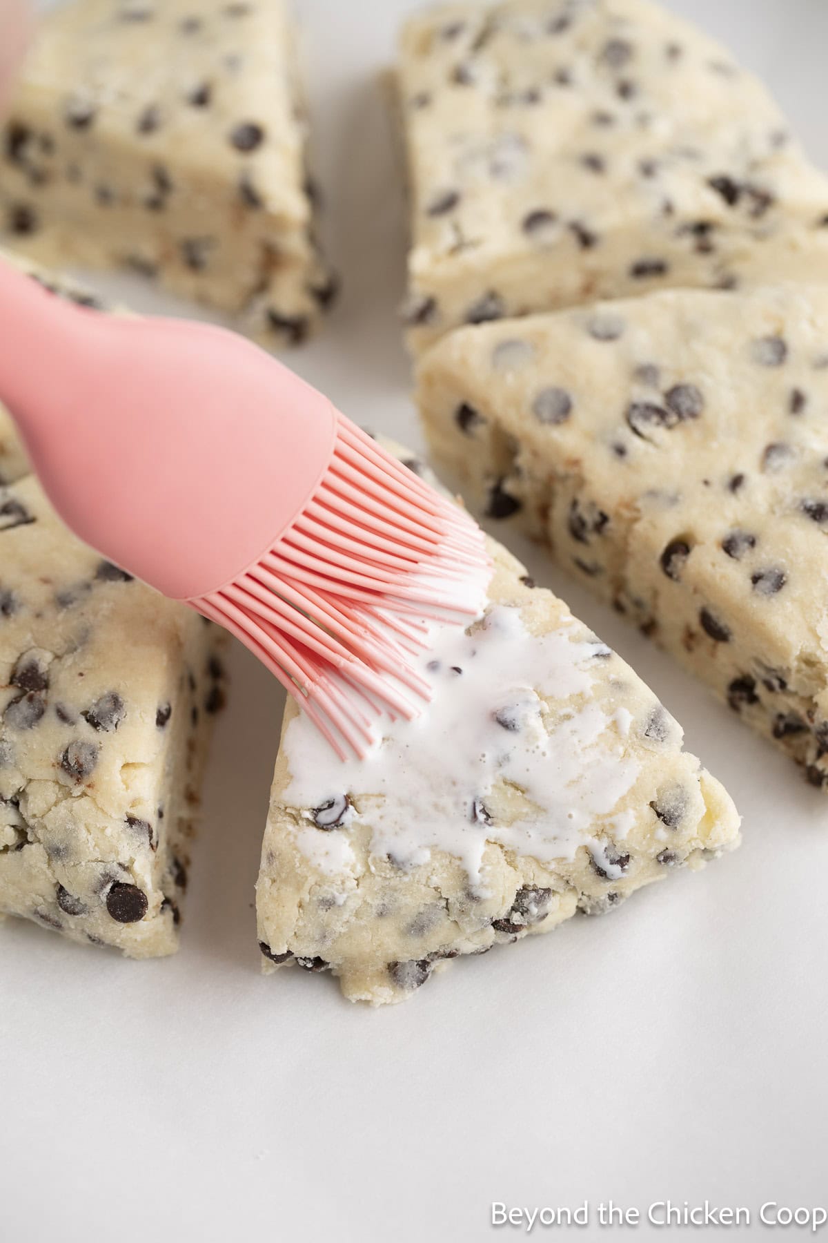 Brushing cream on top of unbaked scones.