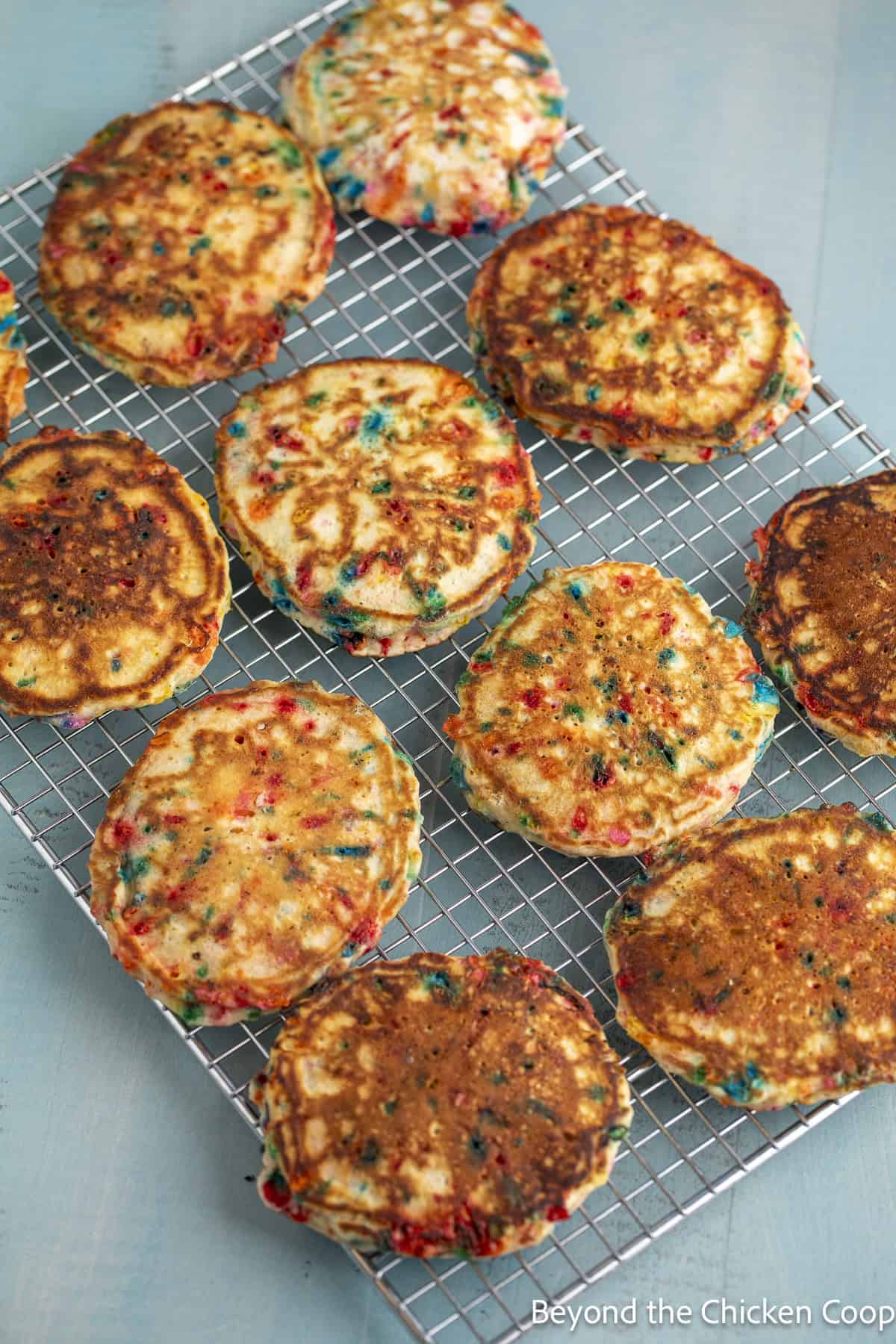 Rainbow sprinkle pancakes on a cooling rack.