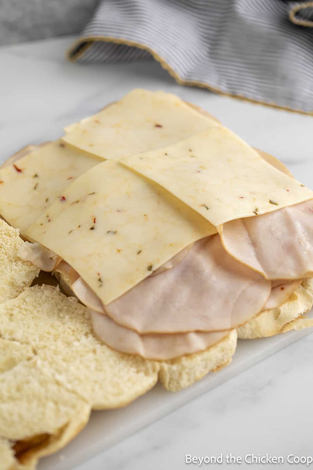 Sliced turkey and cheese on slider buns.