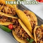 Hard taco shells filled with turkey meat filling arranged on a platter.