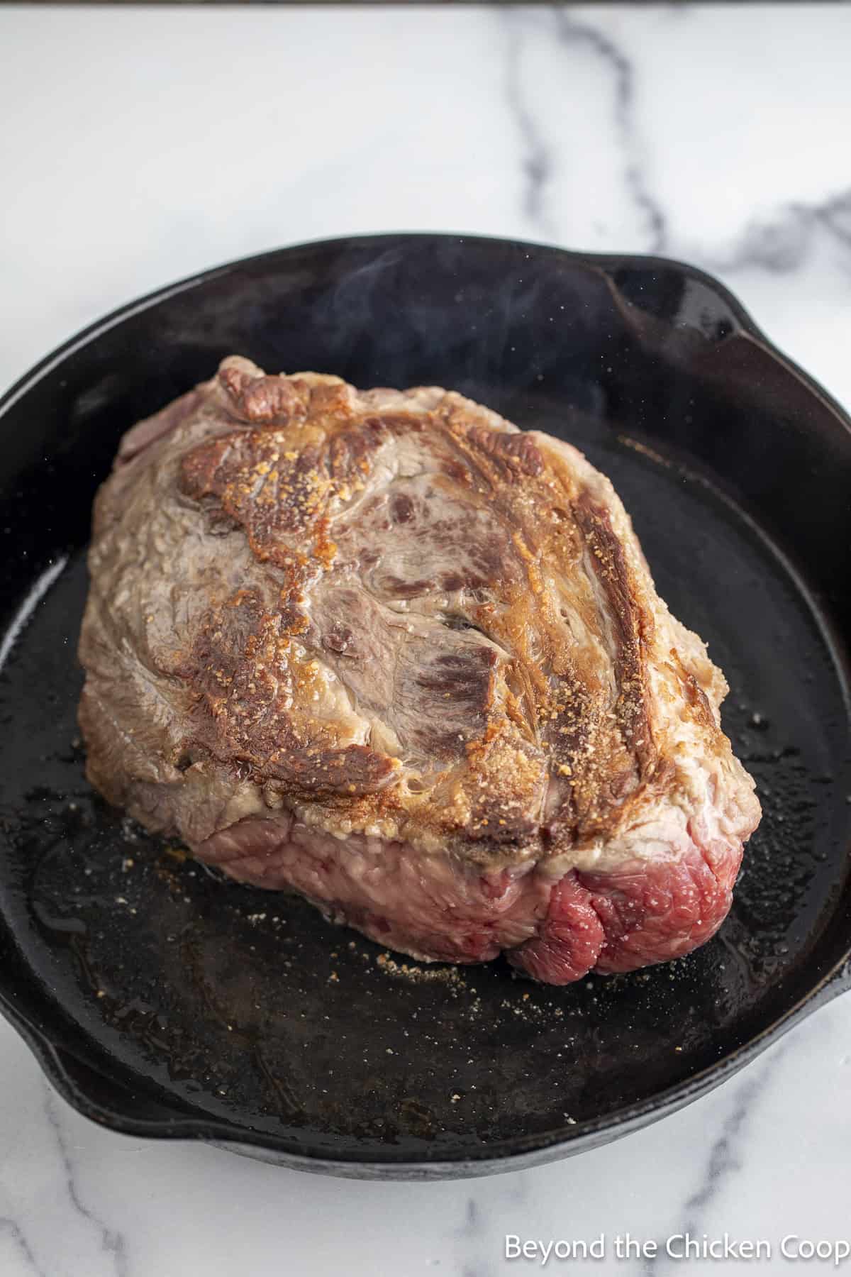 Browning a chuck roast in a cast iron skillet.