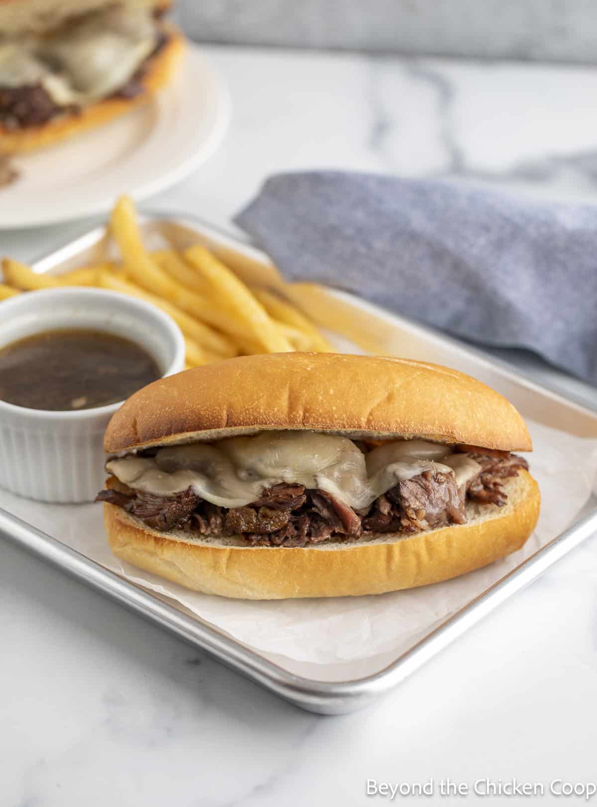 A hot beef sandwich on a plate with French fries.