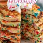 A stack of rainbow sprinkle pancakes topped with whipped cream.