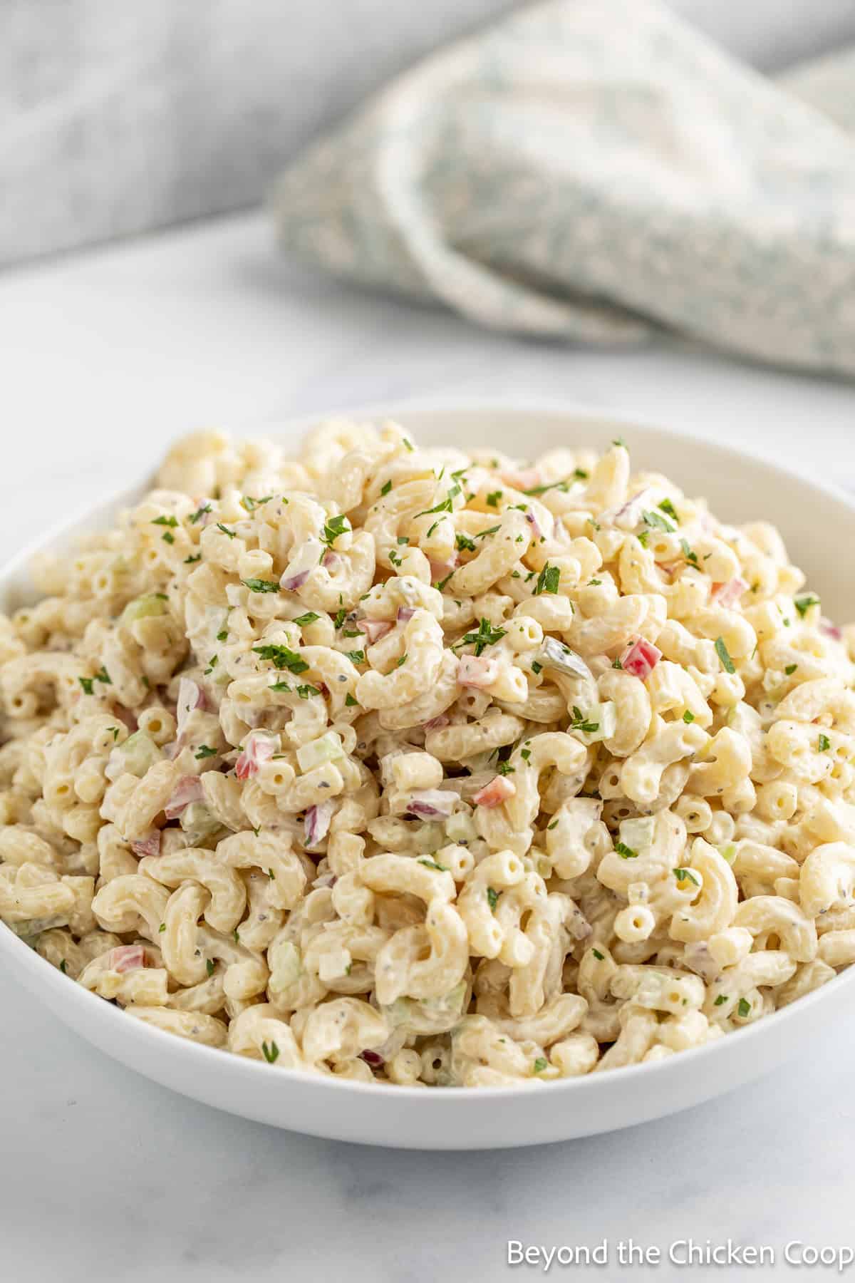 A white bowl filled with an elbow macaroni salad.