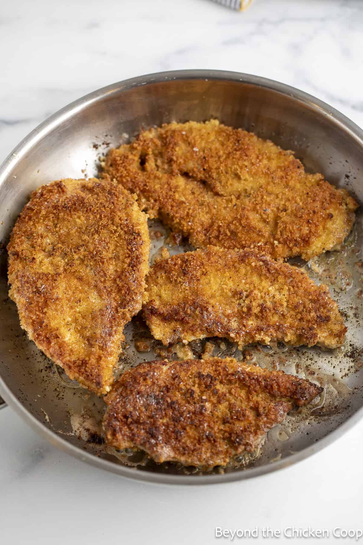 Crispy chicken breasts in a skillet.