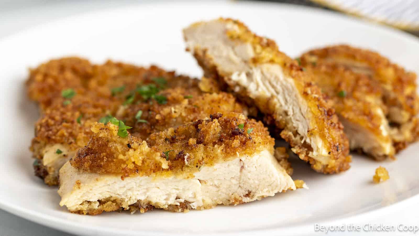 Crispy Chicken breasts sliced thinly on a white plate.