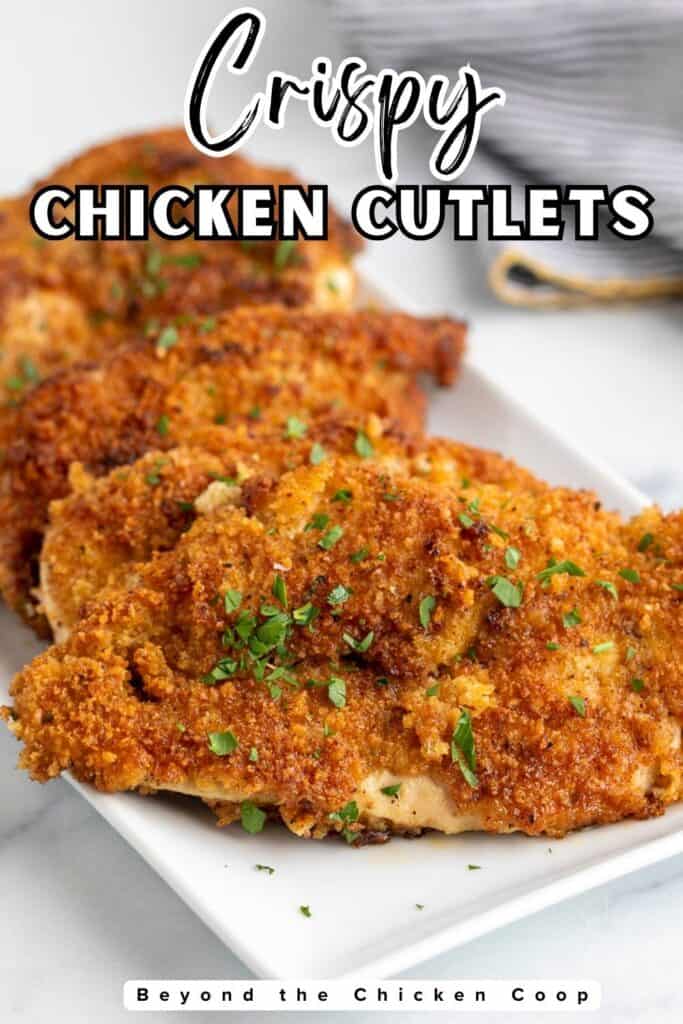 Fried chicken breasts on a white platter.