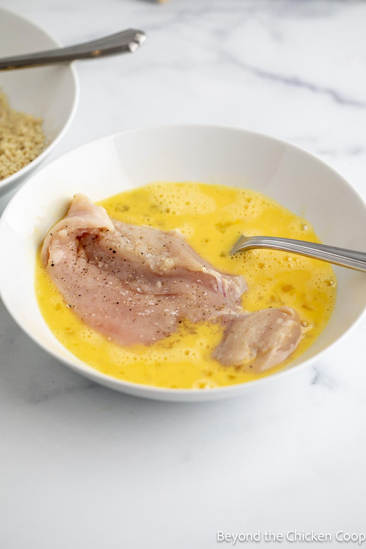 Dredging a chicken cutlet in beaten eggs.