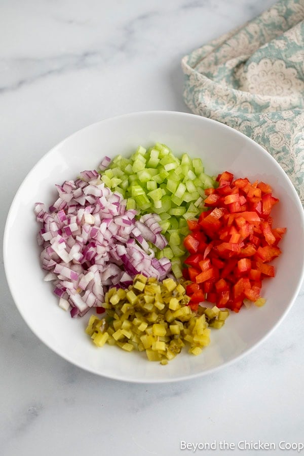 Finely diced fresh veggies and pickle in a white bowl.