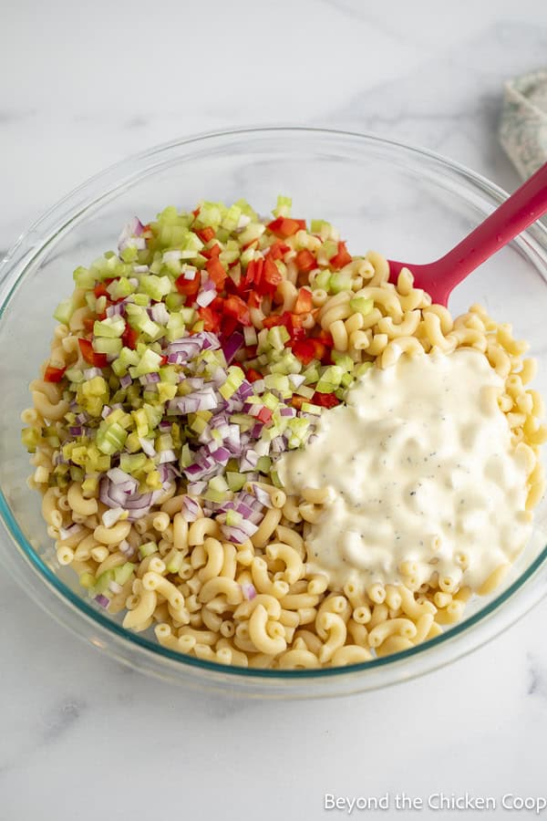 Mixing chopped veggies with elbow macaroni.