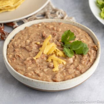 Easy Refried Beans topped with shredded cheese and a sprig of cilantro.