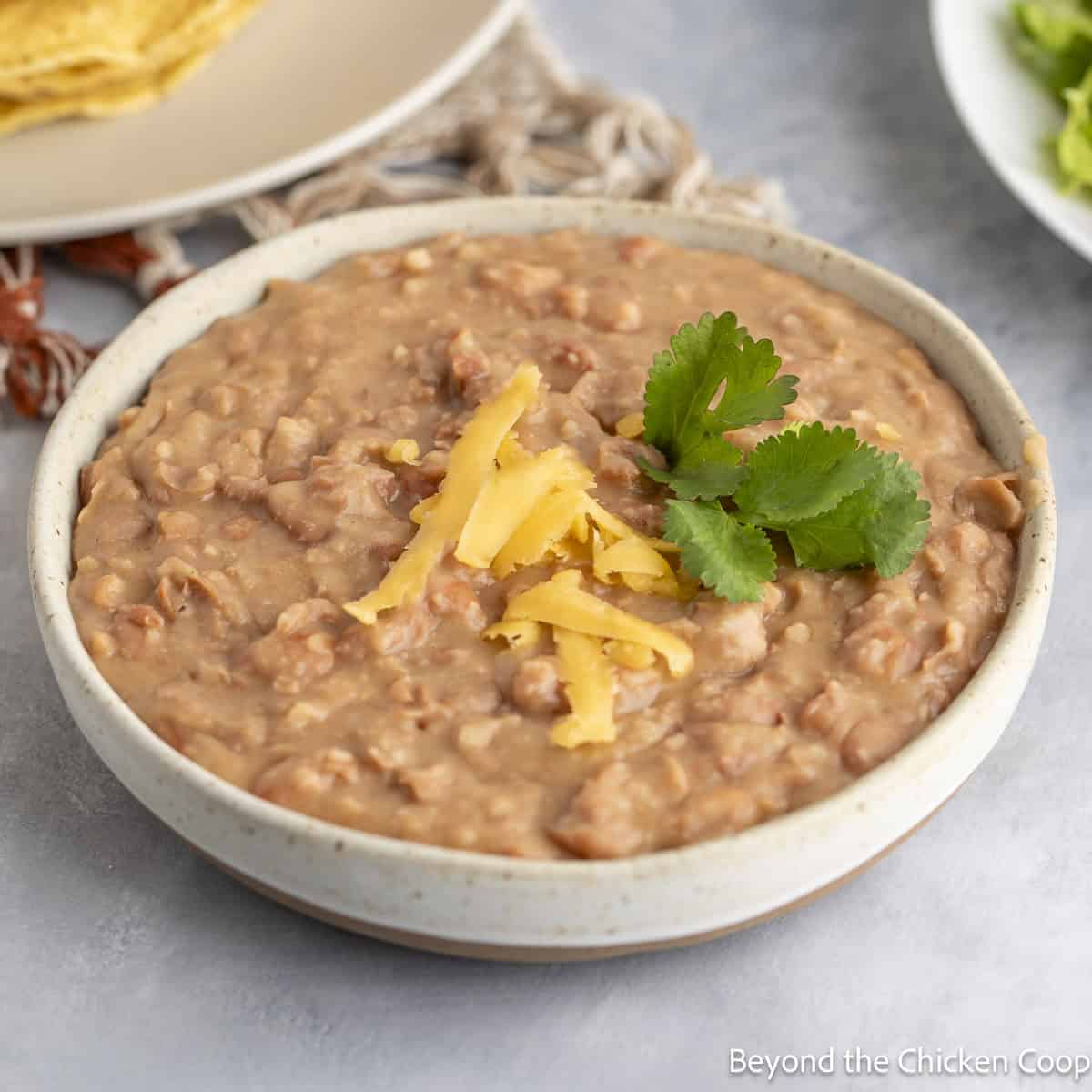 Easy Refried Beans topped with shredded cheese and a sprig of cilantro. 