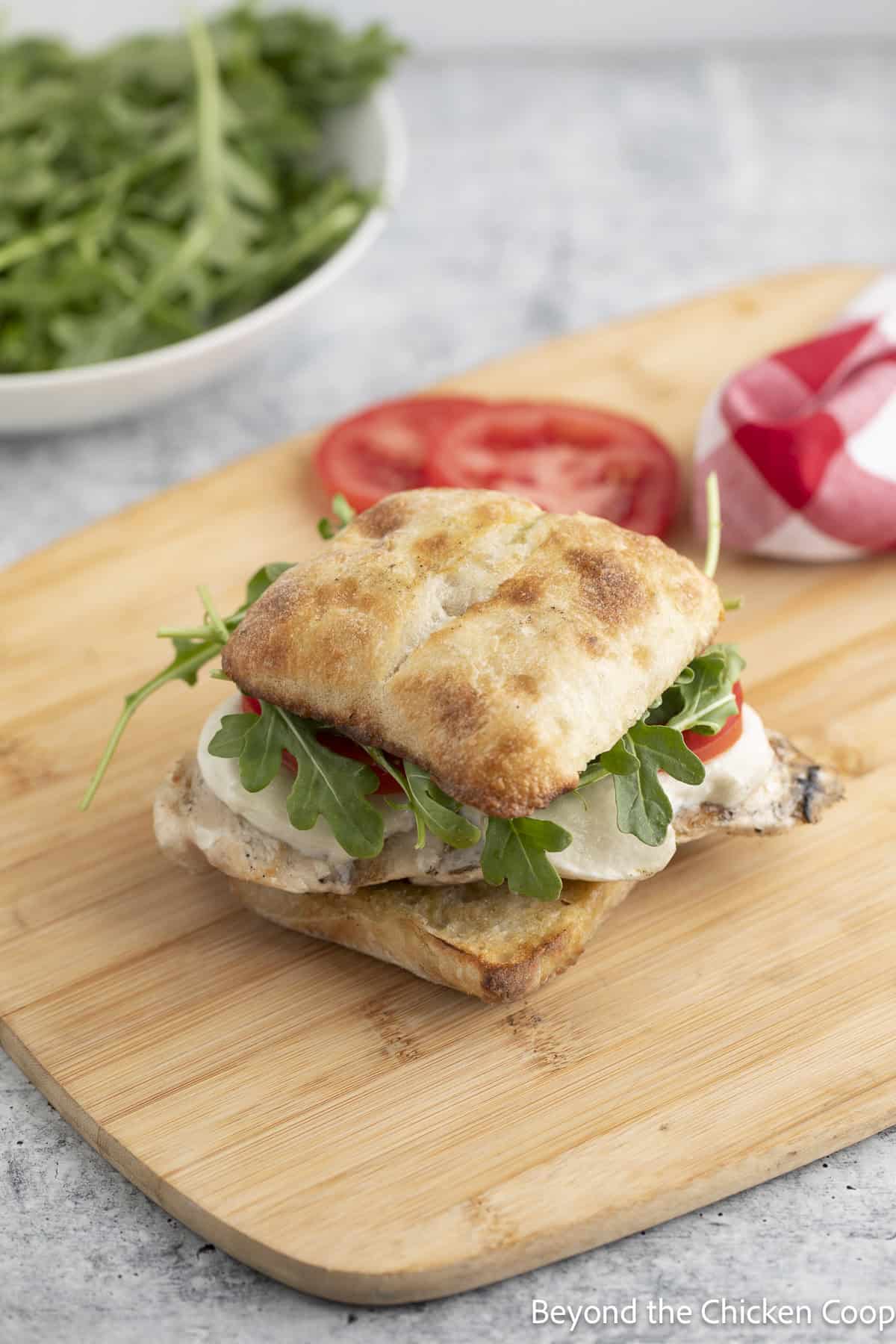 A chicken sandwich on a wooden board.