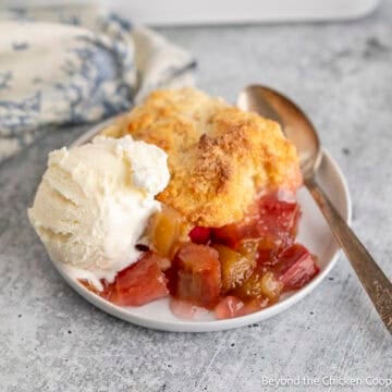 Rhubarb Cobbler with vanilla ice cream on a plate with a spoon.